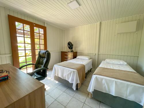 1 dormitorio con 2 camas, escritorio y silla en Casa de Campo no Caruru com açude e piscina, en Tubarão