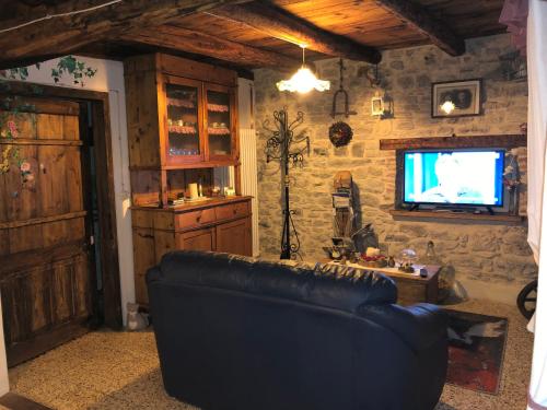 a living room with a leather couch and a tv at CASA ANGELA Stayerat a SEGUSINO Valdobbiadene in Segusino