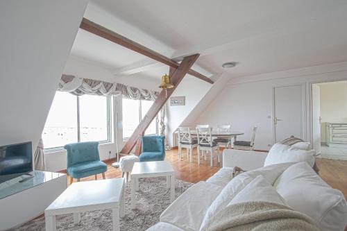 uma sala de estar com um sofá branco e cadeiras em Côté cottage beautiful view to the harbor ! em Étreham