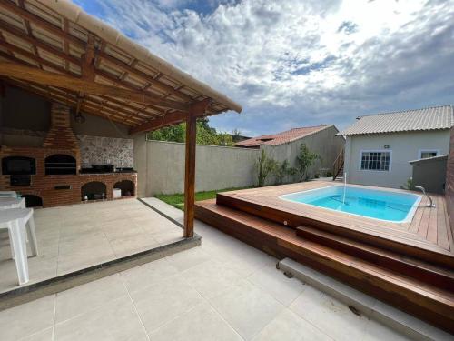 um quintal com uma piscina e um deque de madeira em Casa 4/4 com piscina. em Maricá