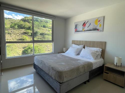 1 dormitorio con 1 cama y 2 ventanas grandes en Trip Monkey Apartments en San Gil