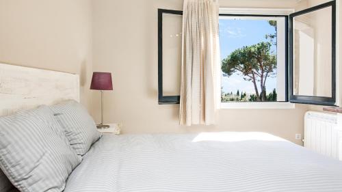 um quarto com uma cama e uma janela com uma árvore em La vinya em Palafrugell