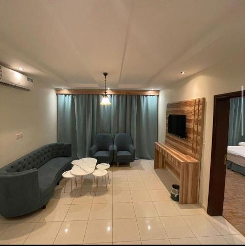 een woonkamer met een bank en een televisie bij Najma ApartHotel in Jeddah