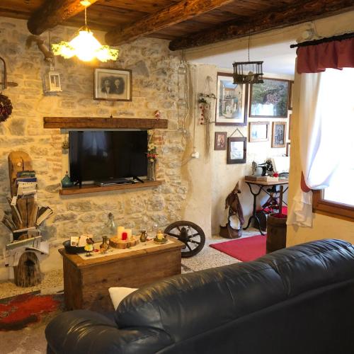 a living room with a leather couch and a television at CASA ANGELA Stayerat a SEGUSINO Valdobbiadene in Segusino
