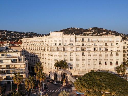 CROISETTE VUE MER LATERALE في كان: مبنى ابيض كبير مع جبل في الخلفية