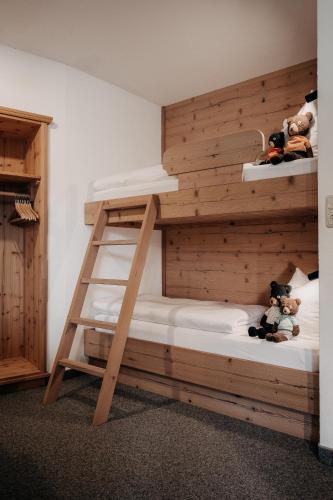 a bunk bed with a ladder and teddy bears at Alpenappartements Cristall in Ehrwald