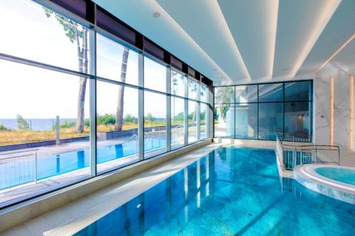 a swimming pool in a building with a large window at Apartamenty The View Hevenia in Rewal
