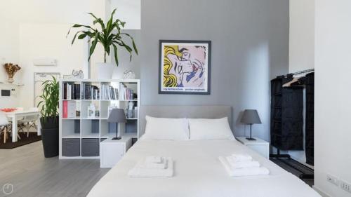 a white bedroom with a large white bed and a plant at Casa Olimpia in Bresso