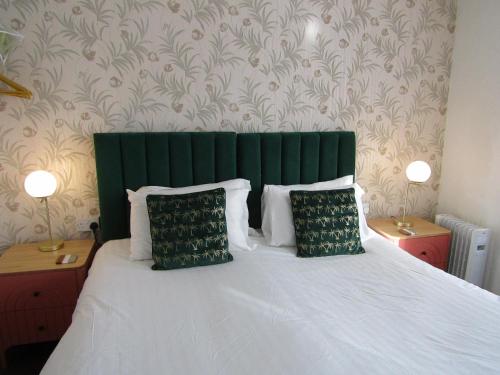 a bed with a green headboard and two pillows at The Scala Hotel in Blackpool