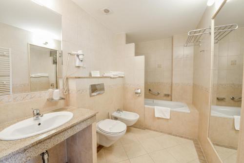 a bathroom with a sink and a toilet and a tub at SPA Hotel Jawor in Jaworze