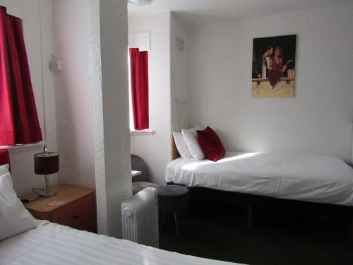 a hotel room with two beds with red curtains at The Scala Hotel in Blackpool