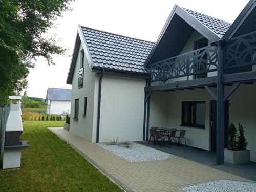 uma casa branca com uma varanda e uma mesa em Domki Biała Mewa Sarbinowo em Sarbinowo