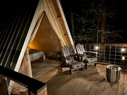 - une terrasse couverte avec 2 chaises et une tente la nuit dans l'établissement Bohamia - Cozy A-Frame Glamp on 268 acre forest retreat, à Talladega