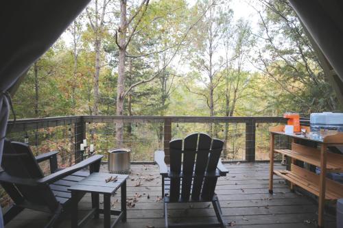 a porch with two chairs and a table on a deck at Bohamia - Cozy A-Frame Glamp on 268 acre forest retreat in Talladega