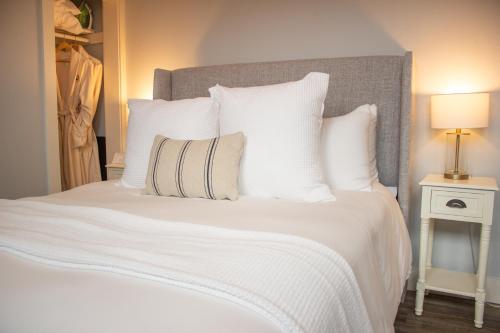 a large white bed with white pillows and a lamp at Douglas On Third in McMinnville