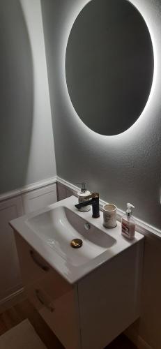 a bathroom with a white sink with a round mirror at Apartament Górski Krokus in Ratułów