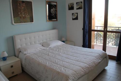 um quarto com uma cama com um edredão branco em CASA VACANZE DA RIKI APPARTAMENTO 2 em Peschiera del Garda