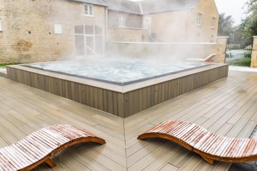 a hot tub on a deck with two benches at Barton Hall Hotel & Spa in Kettering