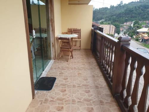 einen Balkon mit Blick auf einen Tisch und Stühle in der Unterkunft Pousada serrano in Monte Verde