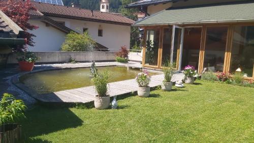 a pond in the yard of a house with potted plants at Adler Hotel-Pension in Fulpmes