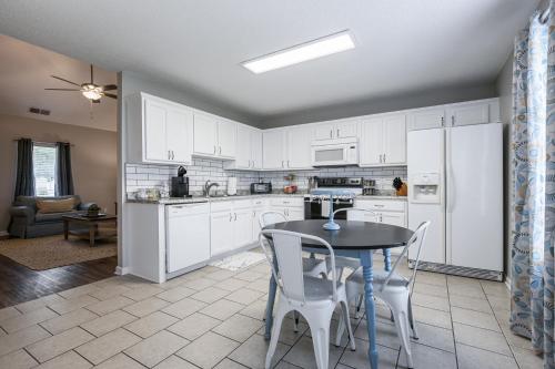 a kitchen with white cabinets and a table and chairs at Lots of Hot Spots & Activities Near This Townhome in Cartersville