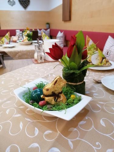 a table with a plate of food and a vase of flowers at Adler Hotel-Pension in Fulpmes