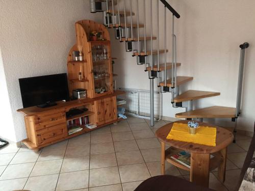 ein Wohnzimmer mit einem TV und einer Wendeltreppe in der Unterkunft Ferienhaus Walther in Erbach