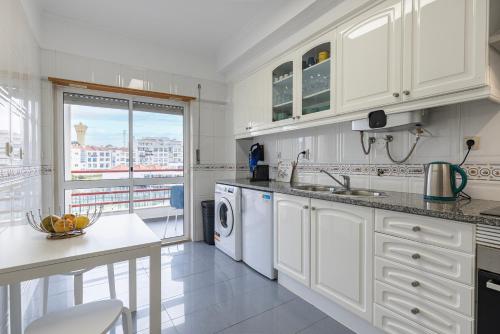 a white kitchen with a sink and a dishwasher at Sunny 2 BDR Apartment by LovelyStay in Charneca