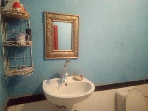 ein Badezimmer mit einem Waschbecken, einem Spiegel und einem WC in der Unterkunft Moha House in Merzouga