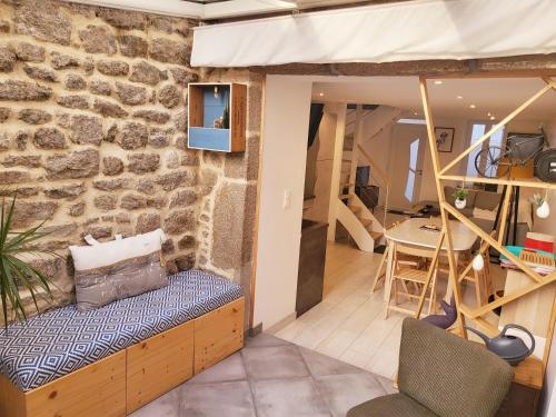 sala de estar con pared de piedra y banco en L'Héméra: Maison au coeur de Barfleur en Barfleur