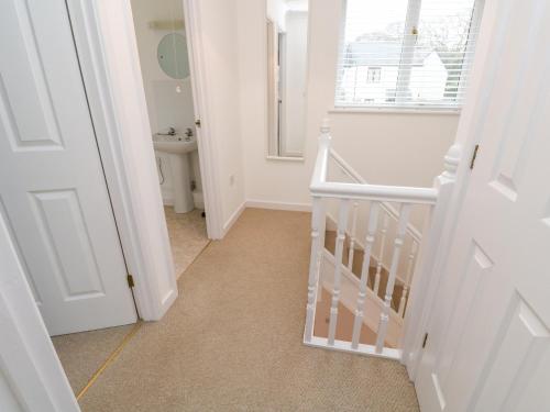 a white hallway with a staircase and a bathroom at Surfers Retreat in Falmouth