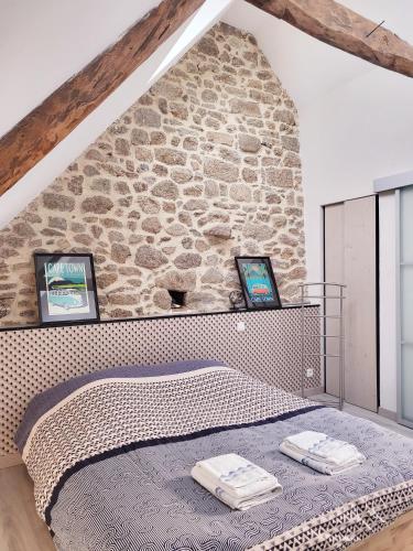 un lit dans une chambre avec un mur en pierre dans l'établissement L'Héméra: Maison au coeur de Barfleur, à Barfleur