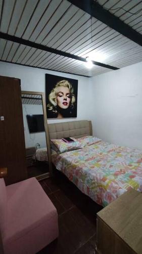 Dormitorio con cama y póster de mujer en Apartamento Cómodo y Familiar, en Medellín