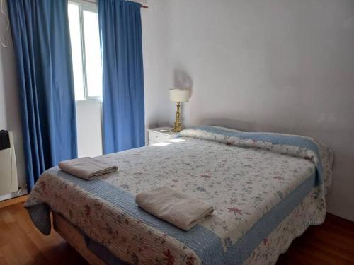 1 dormitorio con 1 cama con cortinas azules y ventana en Departamento Costanera en Gualeguaychú