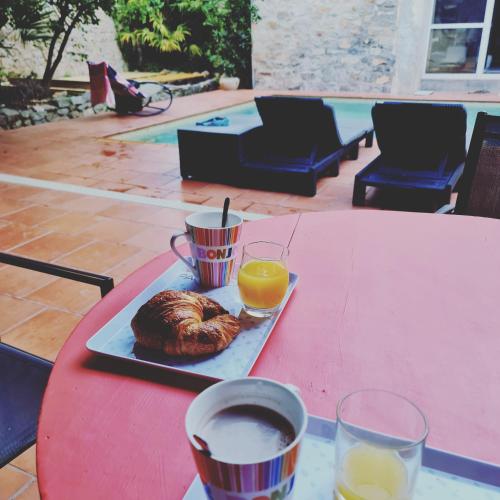 a red table with a plate of food and orange juice at Le Clos de Canet in Canet d'Aude