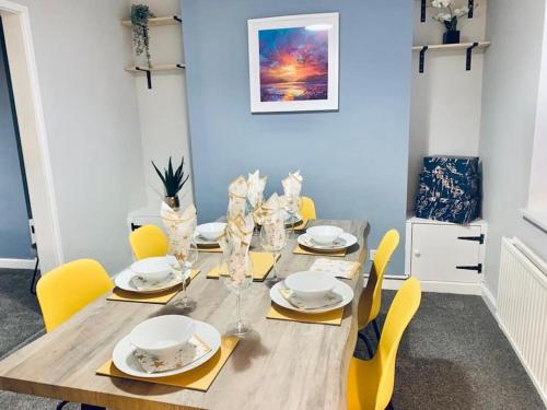 a dining room with a wooden table and yellow chairs at Cosy home near Caerphilly 