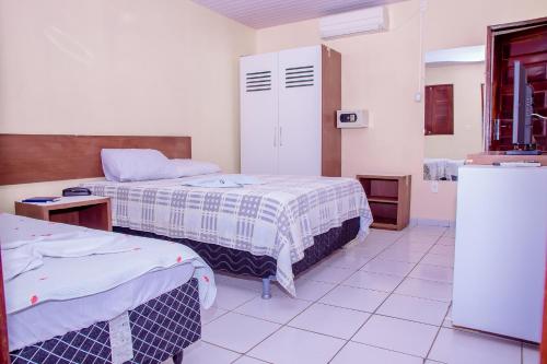 a hospital room with two beds and a refrigerator at Hotel Oásis in Açu