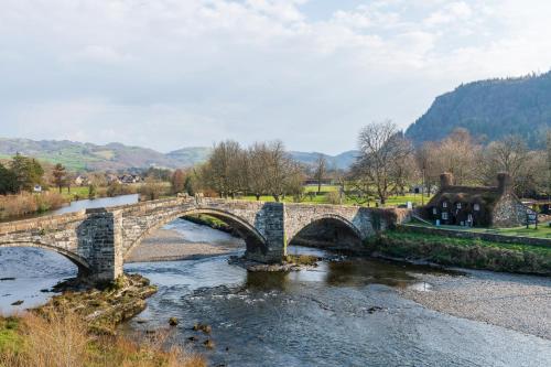 a stone bridge over a river in a park at Glan Conwy House One and Two Bedroom Apartments in Llanrwst