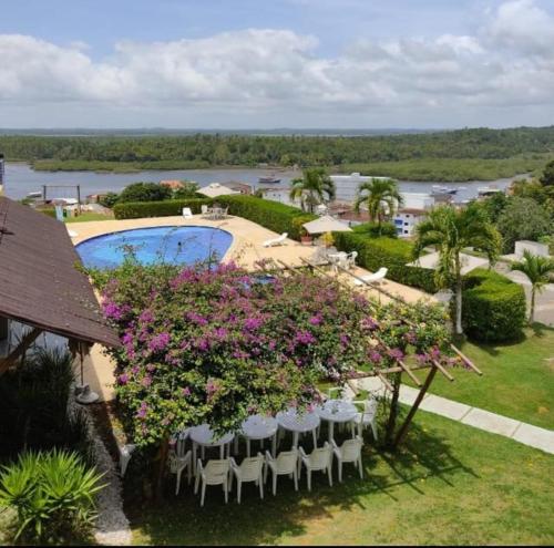 a view of a resort with a pool and chairs and flowers at Hotel Rio Acaraí in Camamu