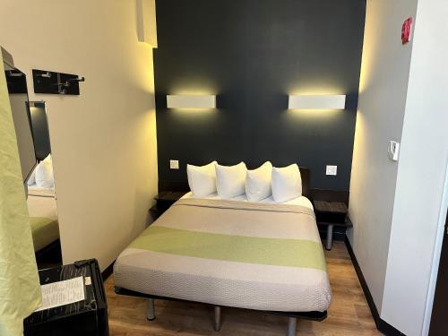 a small bedroom with a bed with white pillows at Feather Factory Hotel in Queens