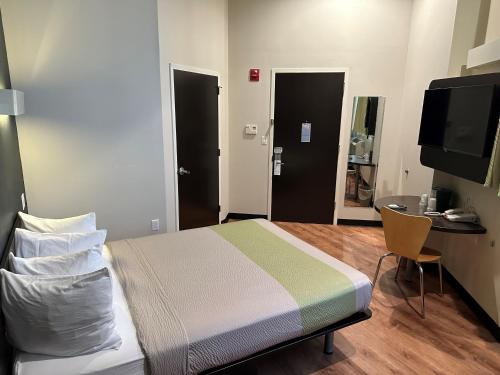 a bedroom with a bed and a table and a television at Feather Factory Hotel in Queens