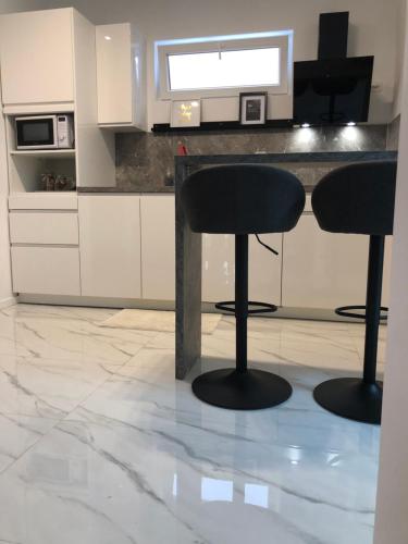 a kitchen with two black bar stools in front of a counter at Apartman FILIPA in Jezera