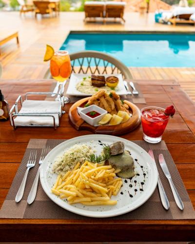 a table with a plate of food with french fries at Jubarte Hotel by Insólito in Búzios