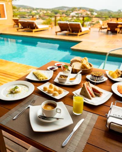 a table topped with plates of food and a cup of coffee at Jubarte Hotel by Insólito in Búzios