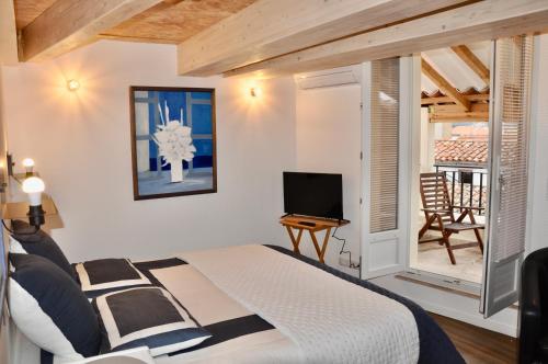 une chambre avec un lit et une télévision et un balcon dans l'établissement les Chambres Tropéziennes, à Sanary-sur-Mer