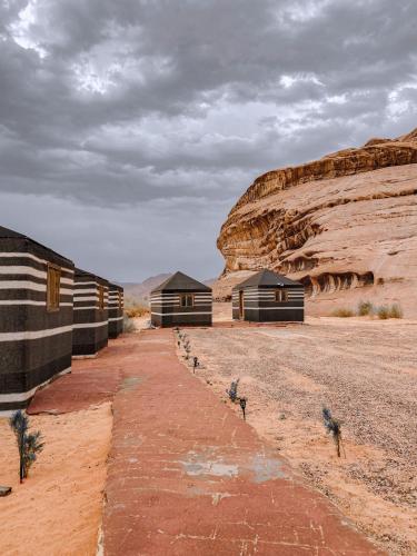 a group of buildings in a desert with a mountain at Syndebad desert camp in Wadi Rum