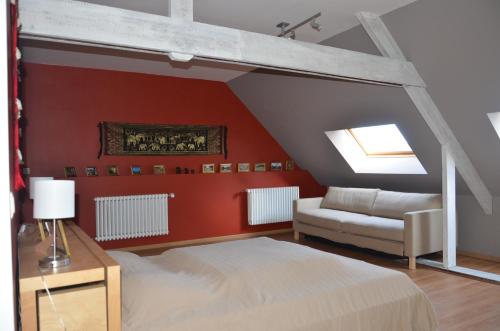 オーステンデにあるHartenhuys Oostendeの赤い壁のベッドルーム1室、ベッド1台、ソファが備わります。
