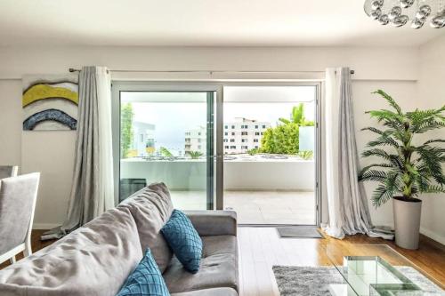 a living room with a couch and a large window at Luxury poolside view apartment in Funchal