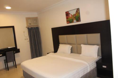 1 dormitorio con cama con espejo y escritorio en Al Massah Al Khalijiyah Furnished Units en Dammam