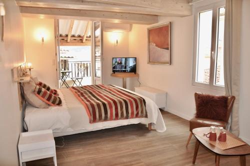 une chambre avec un lit, une télévision et une chaise dans l'établissement les Chambres Tropéziennes, à Sanary-sur-Mer